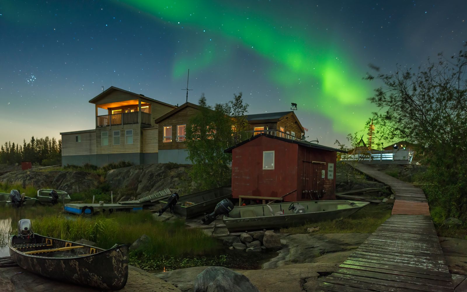 Aurora borealis above lakeside cabins in Yellowknife