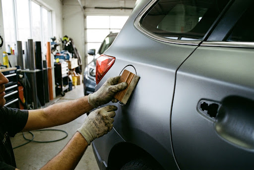 Installer applying vinyl film to a vehicle panel
